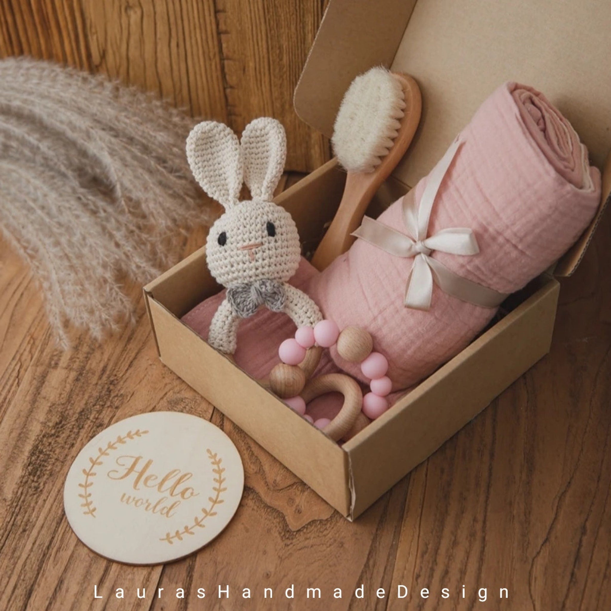 Baby gift set with pink blanket, crochet bunny, and wooden teething ring in a box