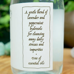 Hydrosol bottle with white label, black text, and clear liquid inside, for cleansing