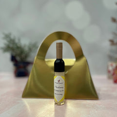 Lip gloss bottle with black and gold cap, yellow label, and gold background, Chamomile Botanicals text