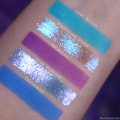 Swatches of eyeshadow in blue, purple, and sparkly silver, applied on skin, with text labels