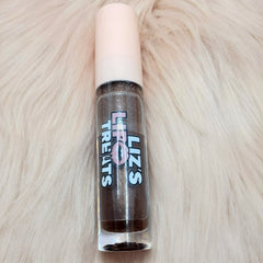 Lip gloss tube with brown glitter, pink cap, and "Liz's Treats" label on a fluffy white surface