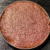 Pressed eyeshadow pan with rose gold duochrome glitter in a 26mm round compact