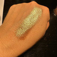 Close-up of light gold and champagne duochrome glitter eyeshadow pan showing shimmering metallic finish