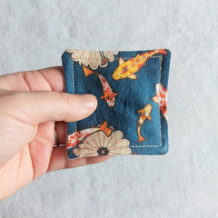 Makeup remover pad, blue fabric with fish pattern, held in hand