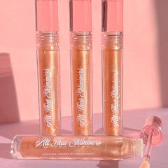 Lip gloss tubes in peach and pink with "All That Shimmers" text, clear applicator, PinkishPurrple brand
