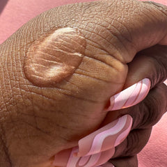 Hand with brown skin, pink and white swirl pattern nails, pink background