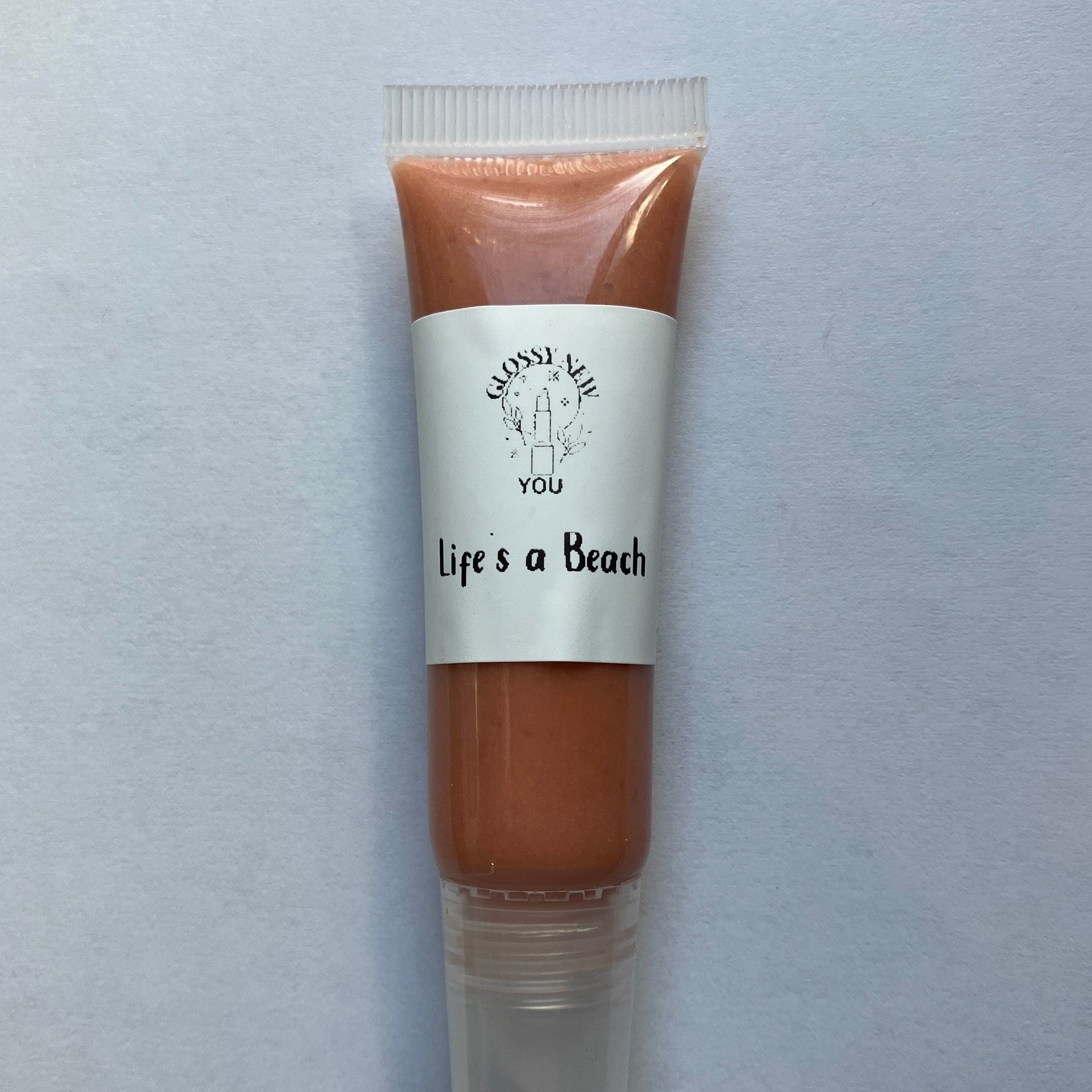Lip gloss tube with peach color, clear plastic, and "Life's a Beach" text from Glossy New You