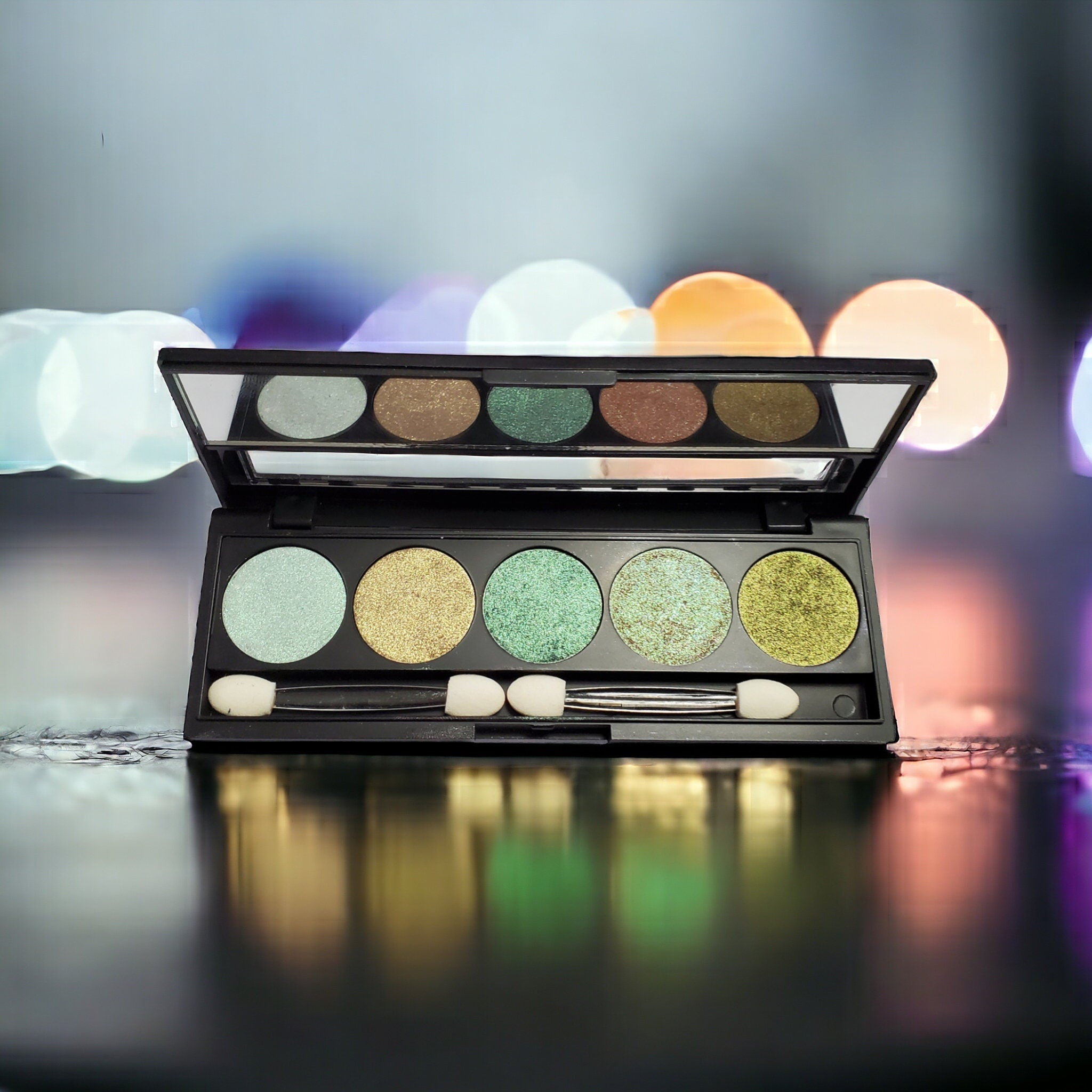 Five-pan refillable eyeshadow palette with duochrome shades in metallic packaging, shown open from above