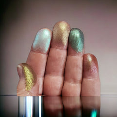 Close-up of five duo-chrome eyeshadows in a refillable palette showing metallic pink, gold, green, blue, and purple hues