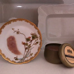Floral plate with gold trim, floral pattern, and white background, next to a jar of balm.