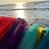 African sponge net in red, purple, green, and yellow mesh material near water