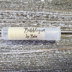 Lip balm tube with clear plastic, white label, and Bubblegum text, on wood background