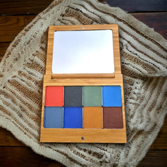 Close-up of warm autumn-toned eyeshadows in matte and shimmer finishes, arranged in floral-inspired palette