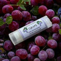 Lip balm tube with white label, clear plastic, and grape flavor text on label