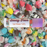 Lip balm tube with "Saucy Face" text, white and purple, over colorful taffy candies