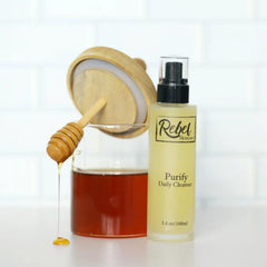 Skincare cleanser bottle with black cap, yellow liquid, and Rebel Skincare brand text