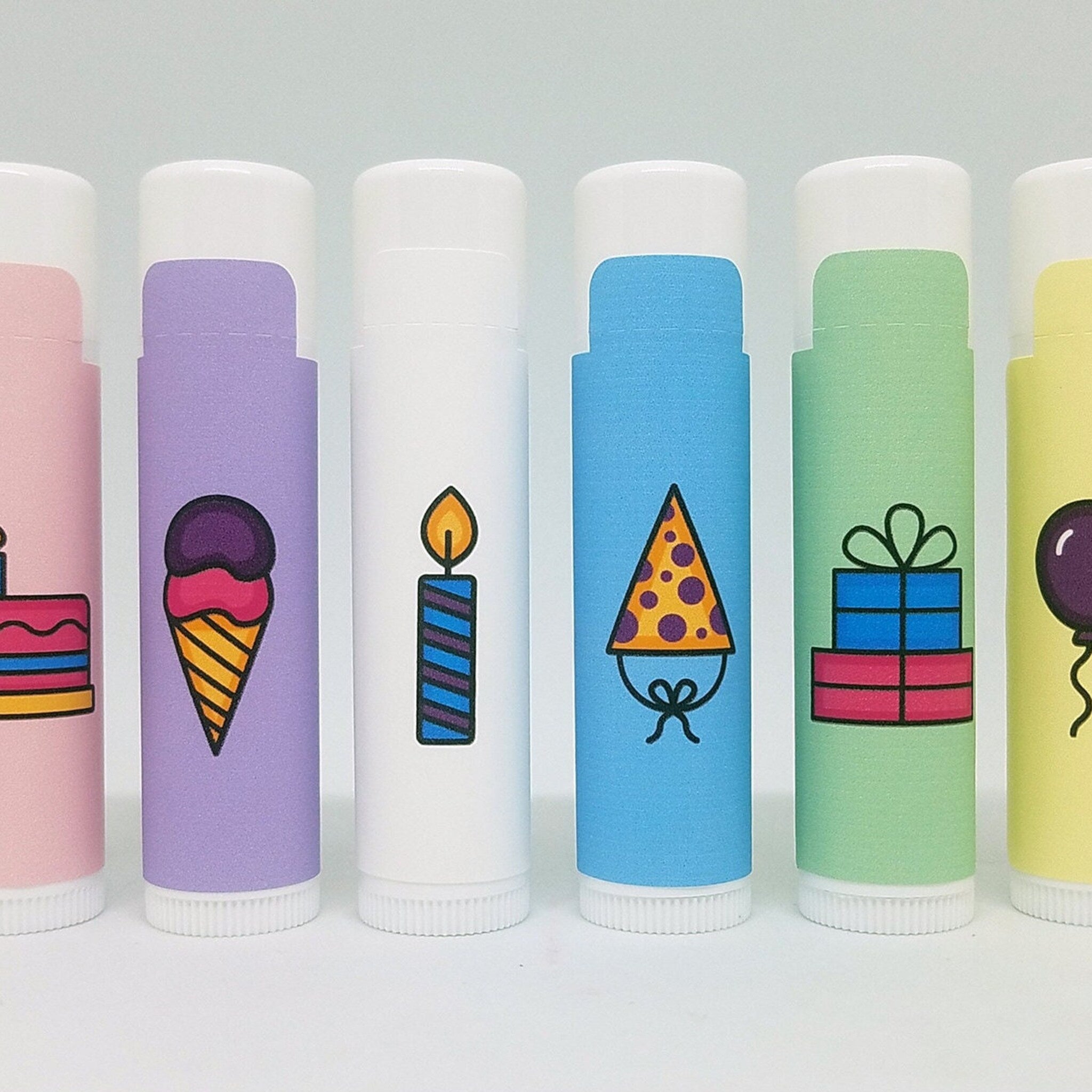 Lip balms with colorful birthday-themed icons on white tubes and caps