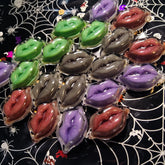 Lip balm shimmer in various colors, lip-shaped containers on black spiderweb background