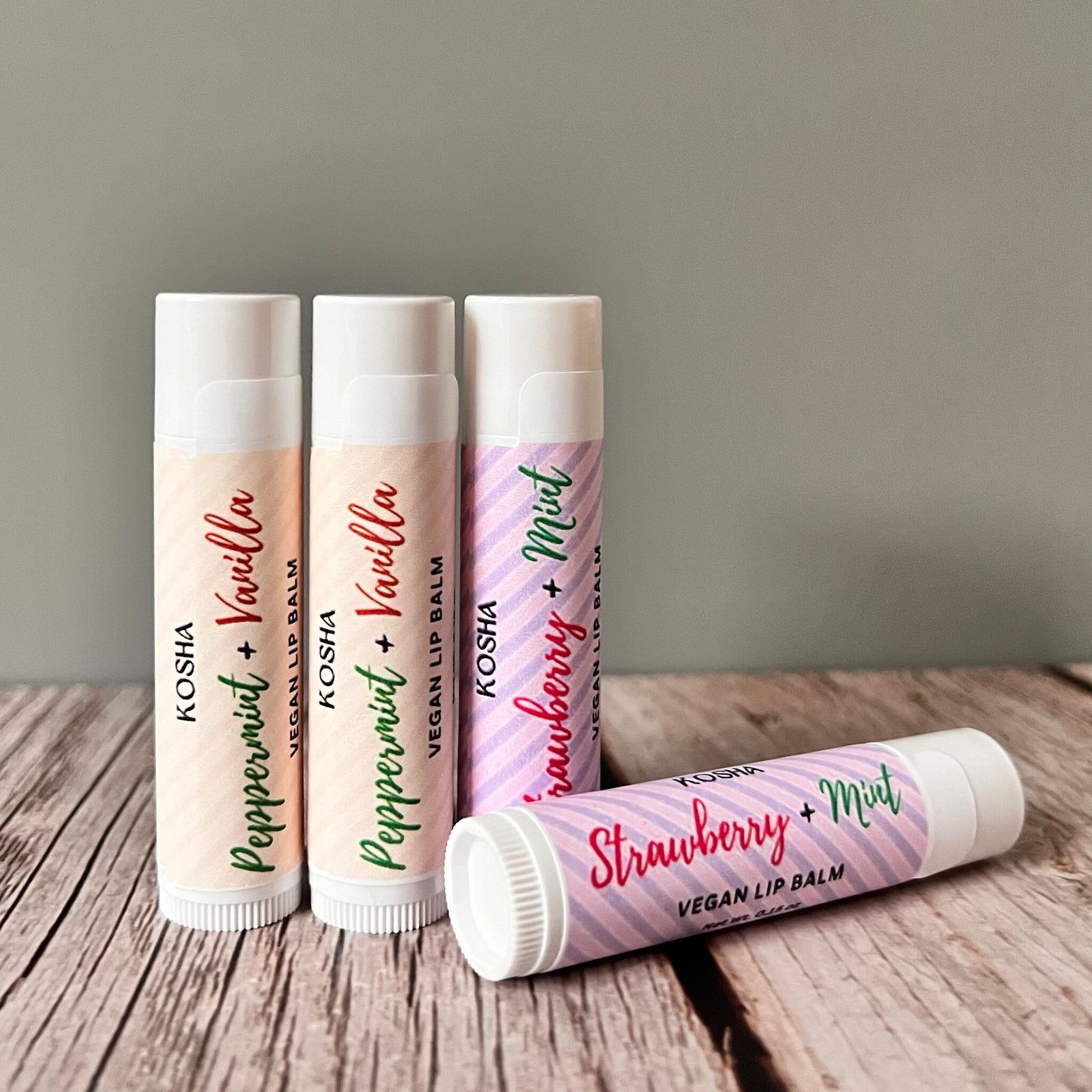 Vegan lip balm tubes in white with colored text and striped pattern, KOSHA brand visible