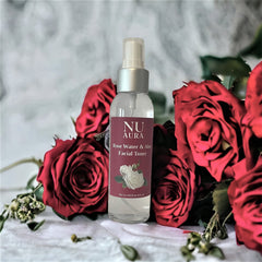 Facial toner bottle with clear glass and silver cap, Nu Aura label, surrounded by red roses