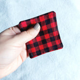 Makeup remover pad, red and black plaid fabric, held in hand