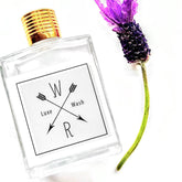 Face cleanser bottle with gold cap, white label, and purple flower next to it WASH brand