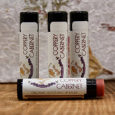 Organic lip balm tubes with black caps, white labels, and "Coppery Cabernet" text