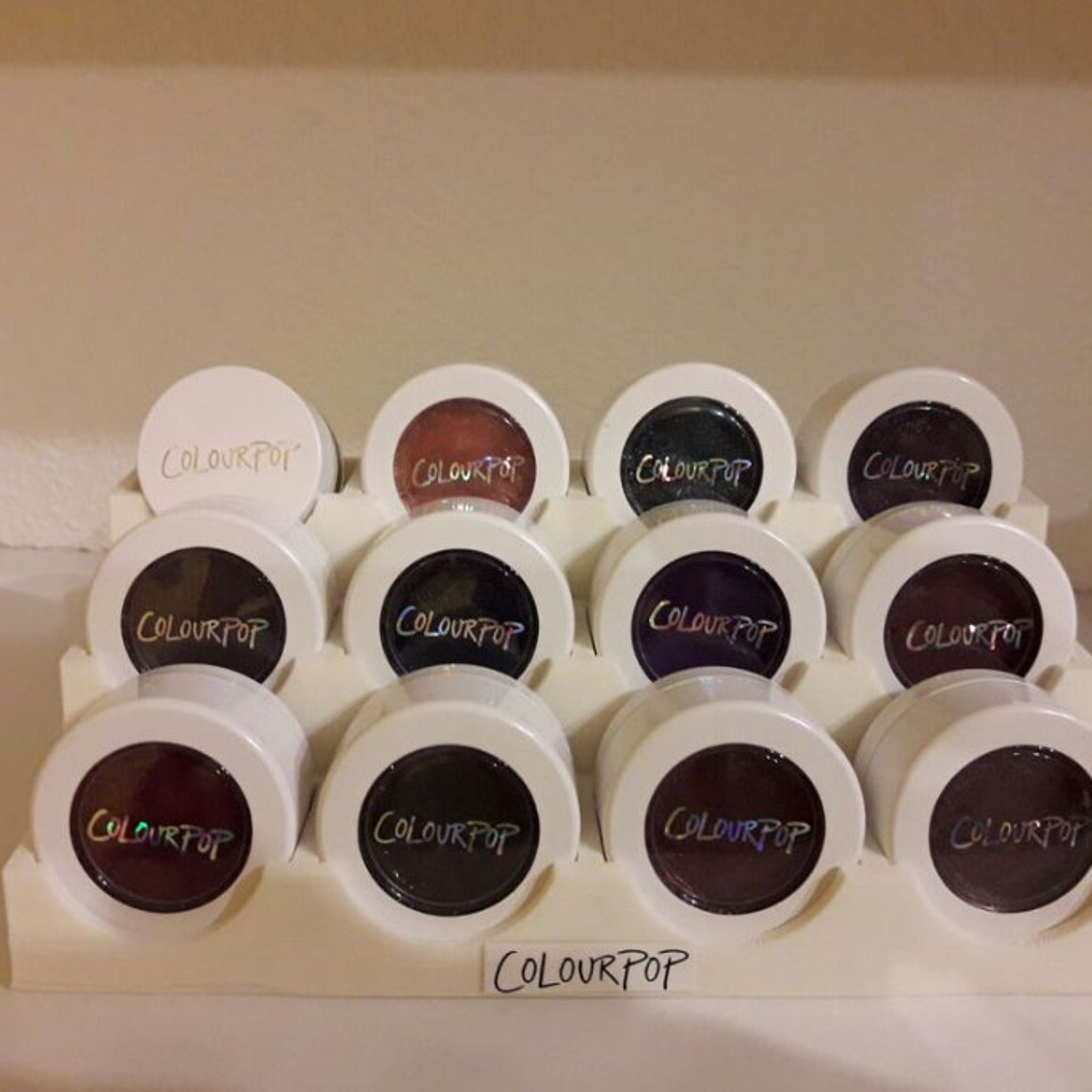 Front view of ColourPop eyeshadow display stand with multiple circular pans in assorted matte and shimmer shades