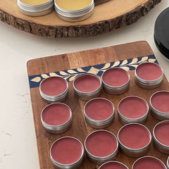 Lip balms in silver tins with red balm on wooden boards