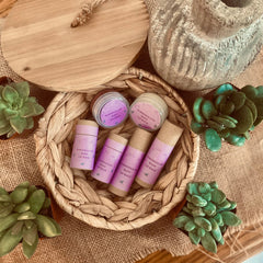 Lip balm tubes with purple labels and brown paper, in a woven basket with My Little Naturals branding