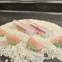 Lip balm tubes, clear plastic, pink and white text, on rice with watermelon candy