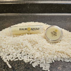 Lip balm, clear tube and jar with Pina Colada label, sitting on white rice