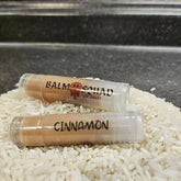 Lip balm tubes with brown balm, clear plastic, and BalmSquadBeauty text on white rice