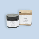 Facial scrub jar with black lid and white label, next to a brown box with Health Nut Beauty text