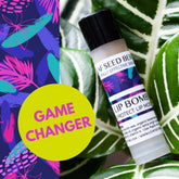 Lip balm tube with black cap, white label, and LeafSeedBerry text, next to green leaves