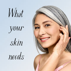 Woman with gray hair and pink top, smiling, touching ear, with text "What your skin needs