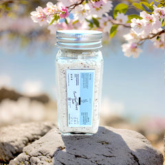 Facial cleansing powder in clear glass jar with silver lid, white powder, and label with brand name
