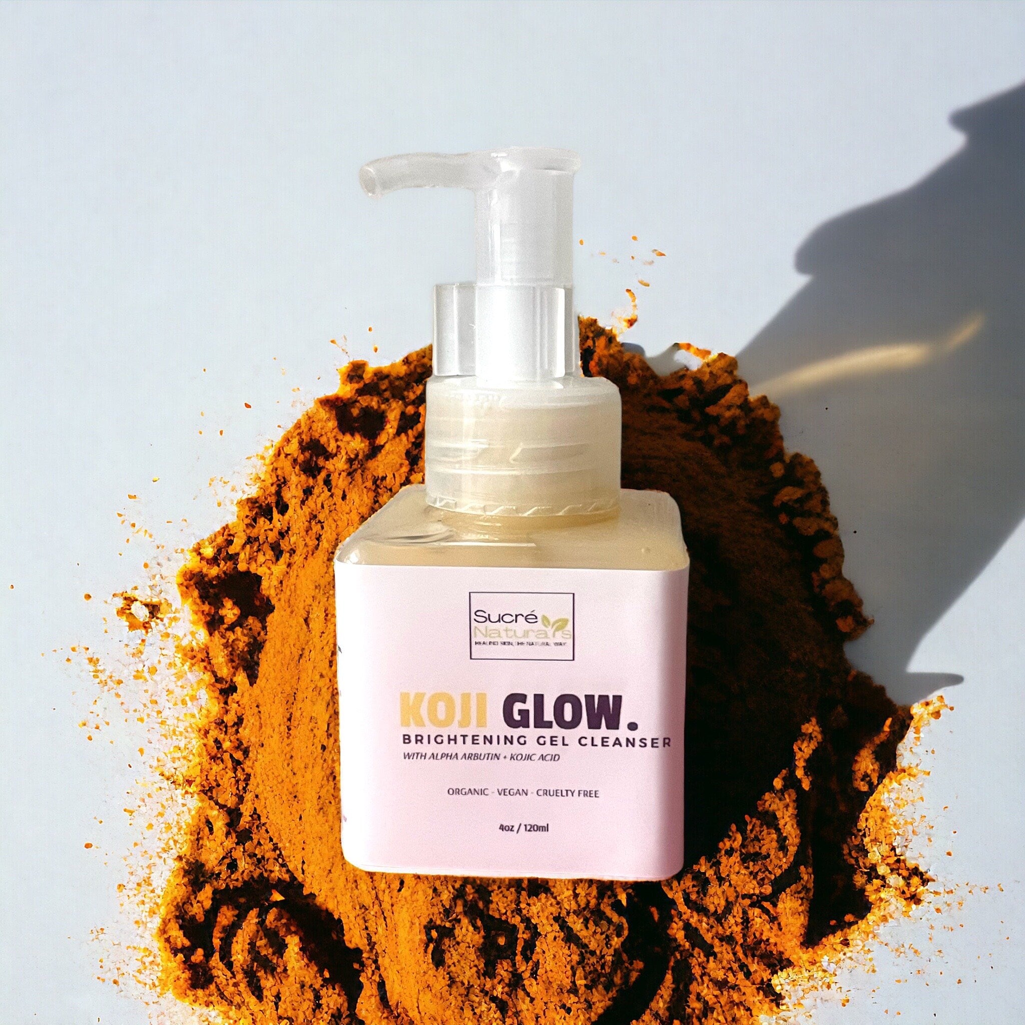Facial cleanser bottle with clear pump, pink label, and orange powder background