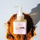 Facial cleanser bottle with clear pump, pink label, and orange powder background