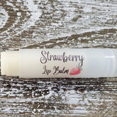 Lip balm tube with white label and "Strawberry Lip Balm" text, on wood background
