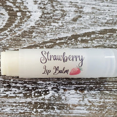 Lip balm tube with white label and "Strawberry Lip Balm" text, on wood background