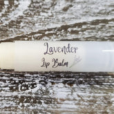 Lavender Lip Balm tube, white with script text, on textured wood surface