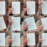 Twelve sleek skincare bottles arranged in a circle, each labeled with a zodiac sign and month, featuring minimalist design