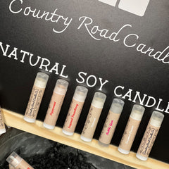 Lip balms with brown and white labels, Country Road Candle Co branding, and clear caps