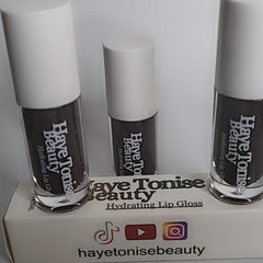 Lip gloss bottles with white caps, brown gloss, and Haye Tonise Beauty branding on display