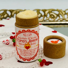 Lip balm tube with beige and pink striped paper, brown cardboard, and visible "CUPID'S ARROW" text.
