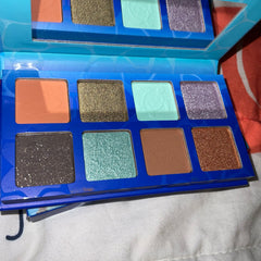 Eyeshadow palette with multiple colors, glitter, and a turtle design on one shade.