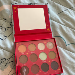 Eyeshadow palette with red case, multiple colors, and a mirror inside for makeup application