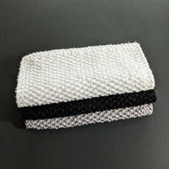 Black and white cotton face cloths folded diagonally, showcasing soft texture against marble surface