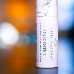 Lip balm tube with white paper, floral design, and "little buddha" text label